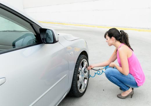 A woman filling her tires up with air and testing their air pressure.